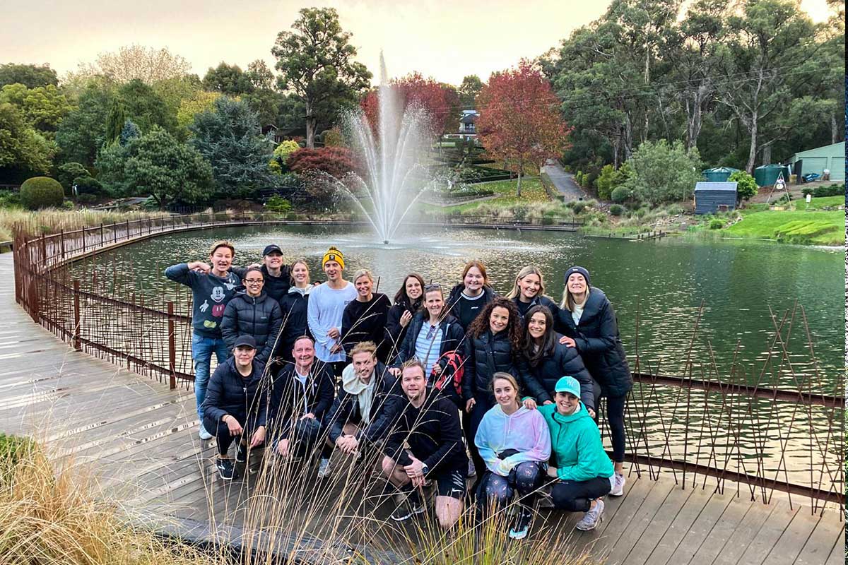 A large group of people standing in front of the lake at Enchanted Adventure with a fountain.
